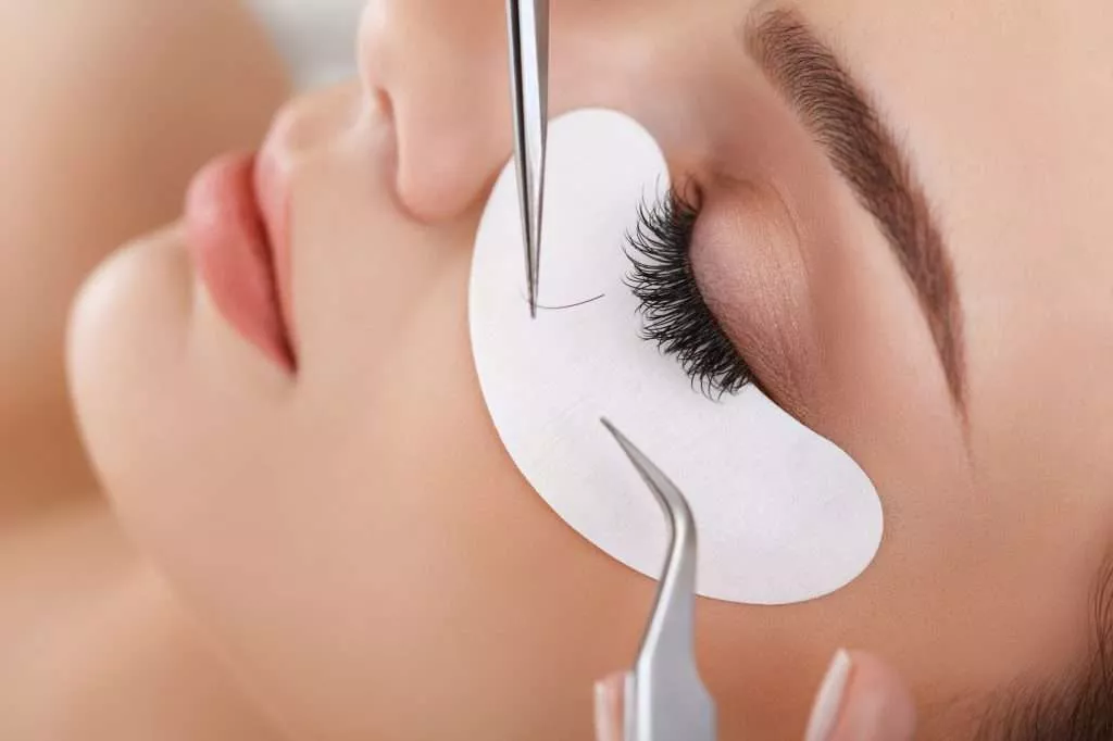 Woman receiving an eye lash extension treatment.