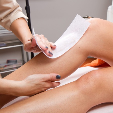 A woman receiving a leg waxing service.