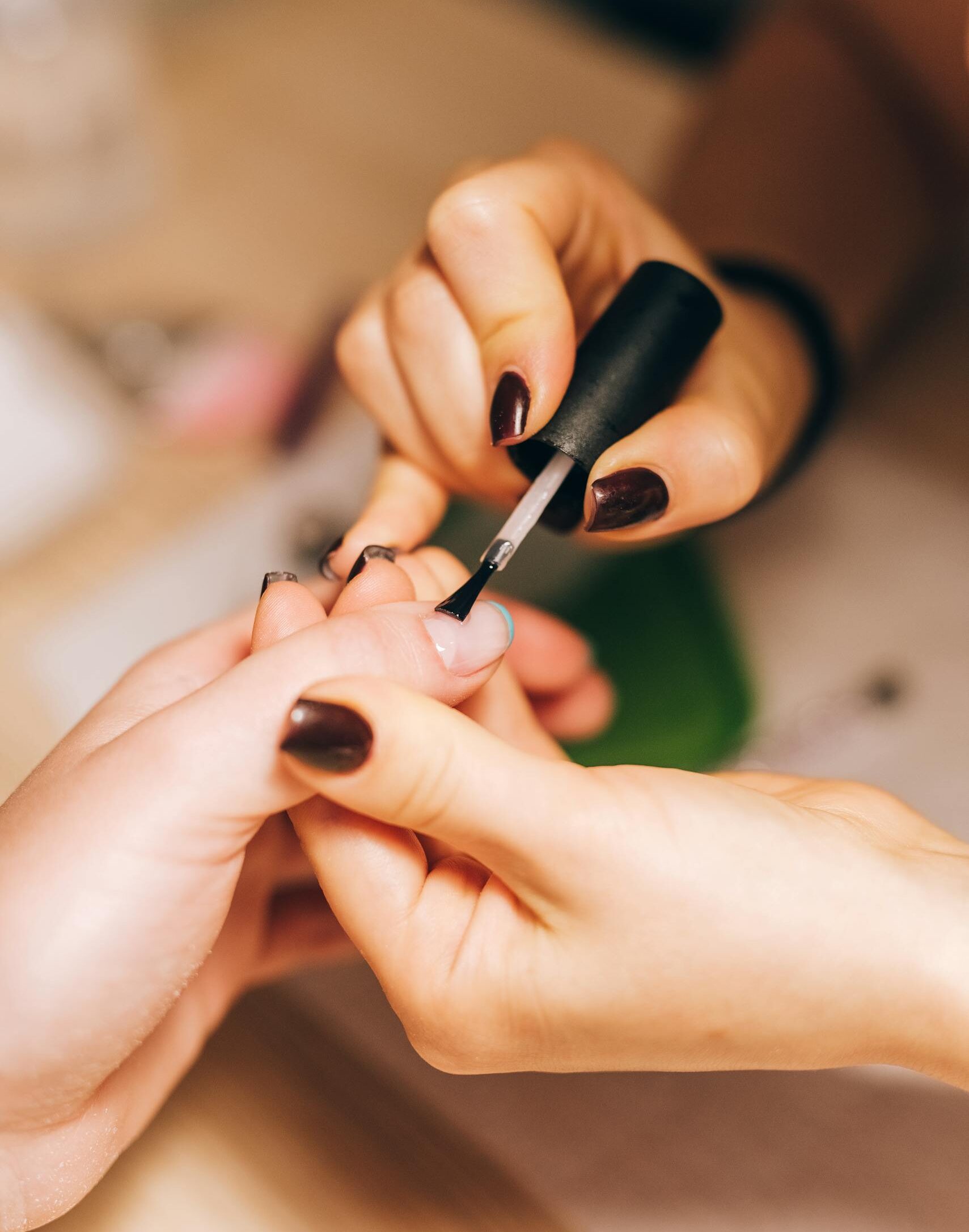 Close-up of a manicurist applying nail polish during a professional manicure session.