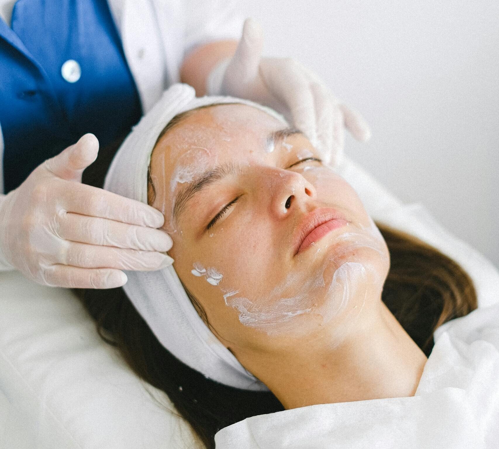 Woman receiving a facial treatment at a spa, promoting skin health and relaxation.